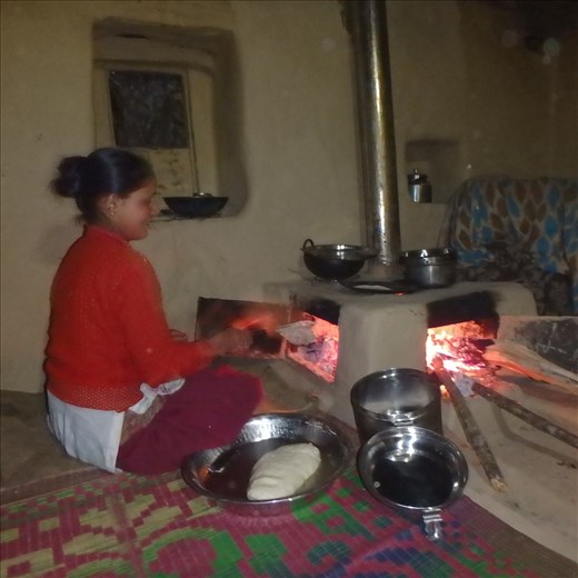 Hansi in roti production. When cooking is finished the roti door is closed and at the end of the night the front door is closed. Radiating thermal mass keeps the room warm through the night. And for the first time windows and doors can be closed!