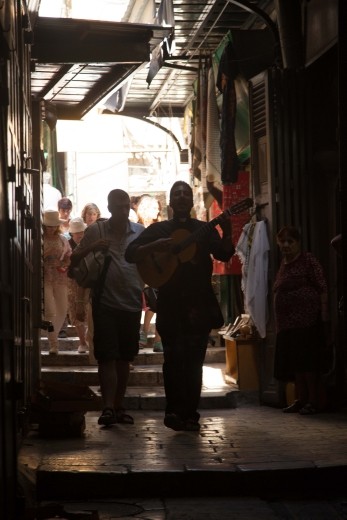 Yes a guitar playing priest leading a procession through ancient corridors along the Via Dolorosa while leading the group in song, within the Old City of Jerusalem, held to be the path that Jesus walked, carrying his cross, on the way to his crucifixion.