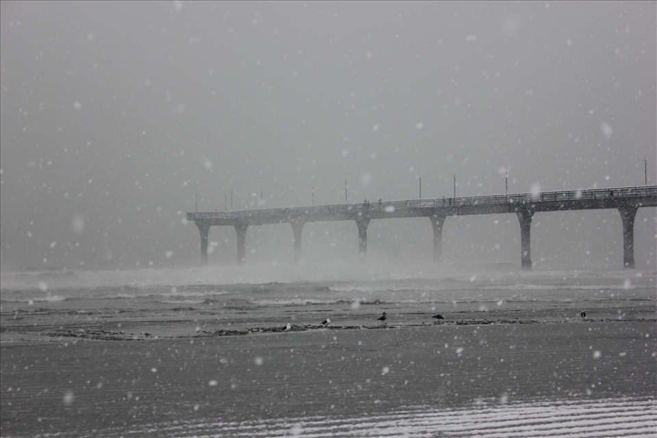 New Brighton Beach/Pier, Christchurch, during a snow storm of one of the coldest winters in Chch in decades. New Brighton is also one of the harder hit suburbs of Chch.
The timing of these two cold winters was difficult because of the earthquakes. Many people did not have warm homes to shelter them and many districts were still being 'zoned' for earthquake repairs or demolition.
During the winter there were many people stuck in limbo with uncertain futures. This pier appears as a bridge to nowhere, which is how many people would have felt about their lives at the time; not knowing if they had a future in Chch or not.
However, the bitter cold made many in the city appreciate the things they still had. The beauty of the small kindnesses and the community pulling together  was important for Chch. This also birthed local superheroes Flat Man and Quake Kid who regularly perform volunteer and charity work for Chch.