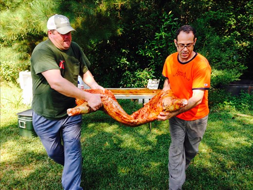 Randy and I carrying half of a pig to the Caja China