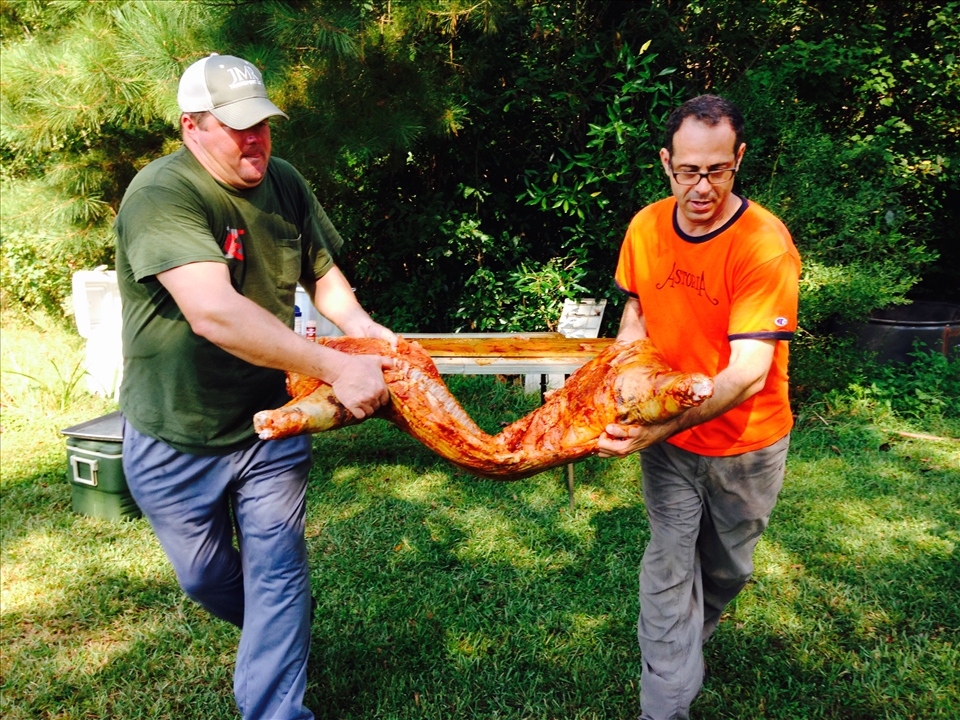 Randy and I carrying half of a pig to the Caja China