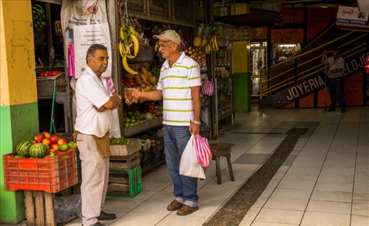 Here are two men talking after haggle some products (one is the seller and the other buyer). In the back, another man is working, sweeping the market. Most of the workers are men, instead of women, as is usually in other markets like this.