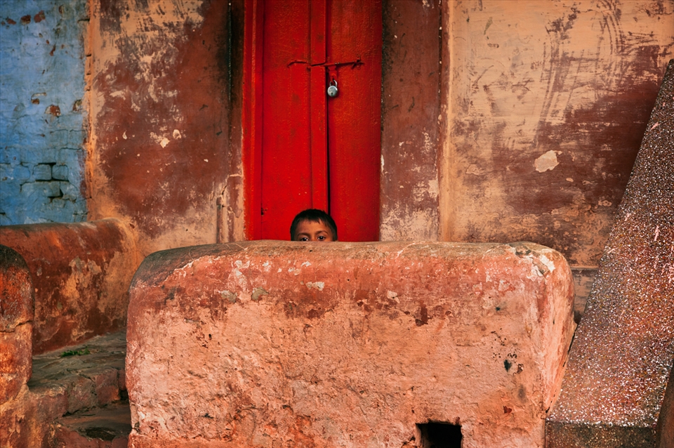 A boy hides whilst checking out the westerners walking down the street.