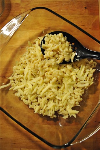 Layering the spätzle in a dish with Gruyere cheese.