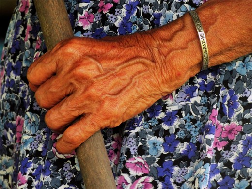 The stick she uses to push her boat through the river and to support herself while walking, is hold by arm that has bracelet with the word 