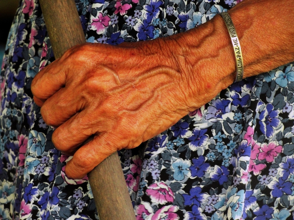 The stick she uses to push her boat through the river and to support herself while walking, is hold by arm that has bracelet with the word 