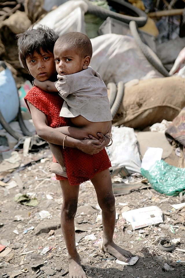 This young girl is left to care for her younger sibling while her parents are working as rag pickers. Children particularly girls are often the primary care givers of younger children, the elderly and the sick.  