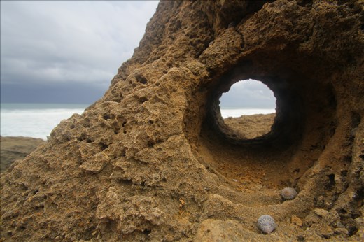 A perfectly round keyhole cut into the coral reef from wind and water.