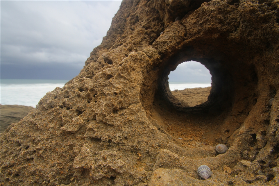 A perfectly round keyhole cut into the coral reef from wind and water.