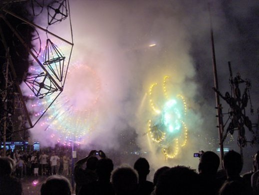 This is a gem of a photo. It is 1am on a hot July Saturday evening.  It is supposed to let off these fireworks one at a time. A spark from the first one has ignited the second attraction unintentionally and  thus one could admire them both being let off together. It can take upto 2 days to setup these big attractions in the village square which will burn out in less than 30 seconds each. These village square fireworks compliment the ones that are let off into the air, the ones we have seen in the other 4 photos of this gallery. By the way, on such a night, in the village square there will be very little room where one can move since thousands of people from all over the island and tourists flock to the Zurrieq village to see such a spectacular show.