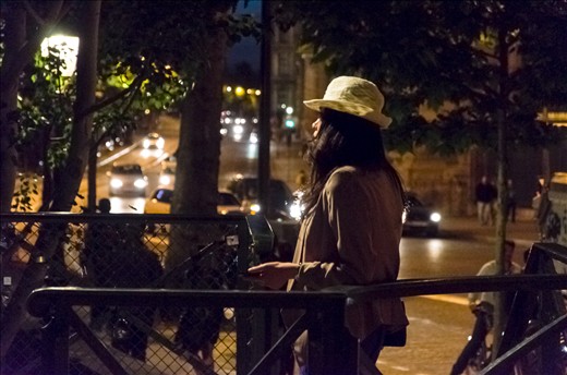 A woman waits for her date by the Pont des Arts over the Seine River.