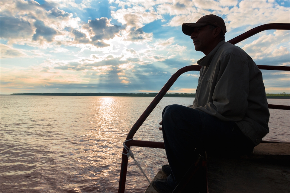 One of passengers of El Junior looks towards the bow as the sun rises 