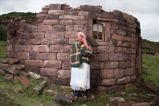 The journeys of daily life in the villages near Masitise in Lesotho, Africa.

The lady stands next to a demolished hut in her village. She is wearing blankets to face the cold in the Mountains. 