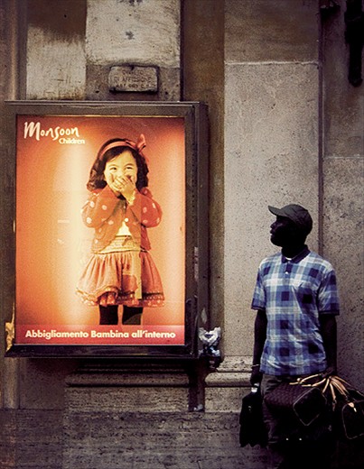 A man selling bags in the street next to a little girl
