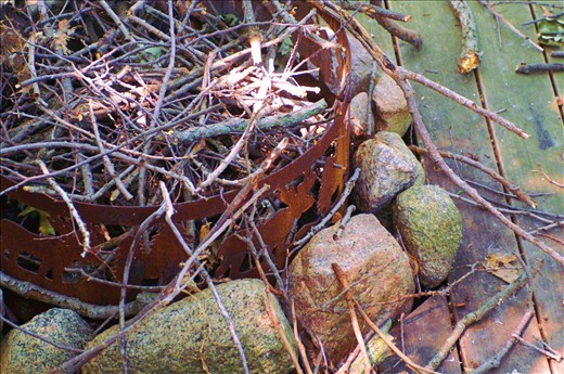 Worn and weather-damaged planks surround a rusting fire ring