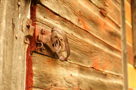 A simple shed positioned near a desolate barn slowly rusts away