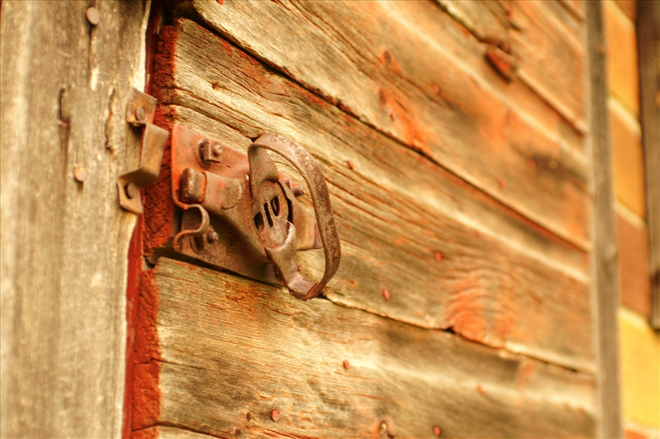 A simple shed positioned near a desolate barn slowly rusts away