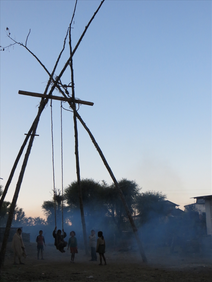 Village children play at dawn on a bamboo swing created for Dashain Festival.