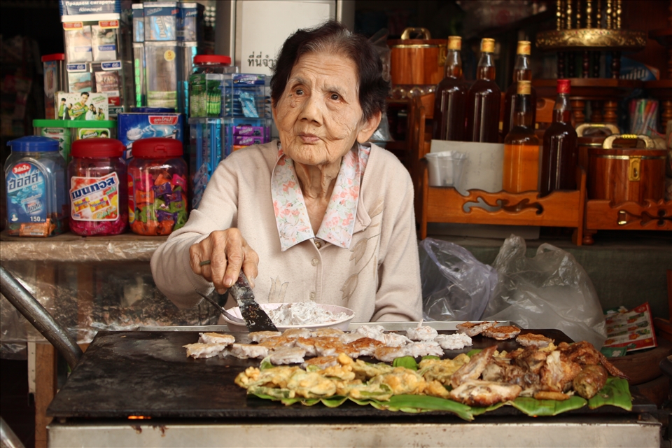 An elderly woman cooks delicious street food in Chiang Mai