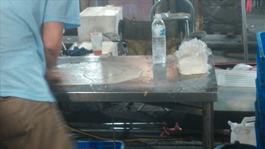 Giant pancake with green onions being prepared