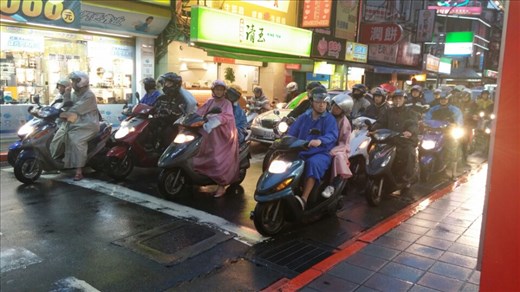 Taipei moped riders undeterred by the rain showers. They just don a poncho and go!