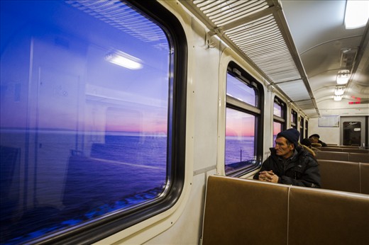 On a Trans-Siberian commuter train, a man admires the morning light on Baikal.