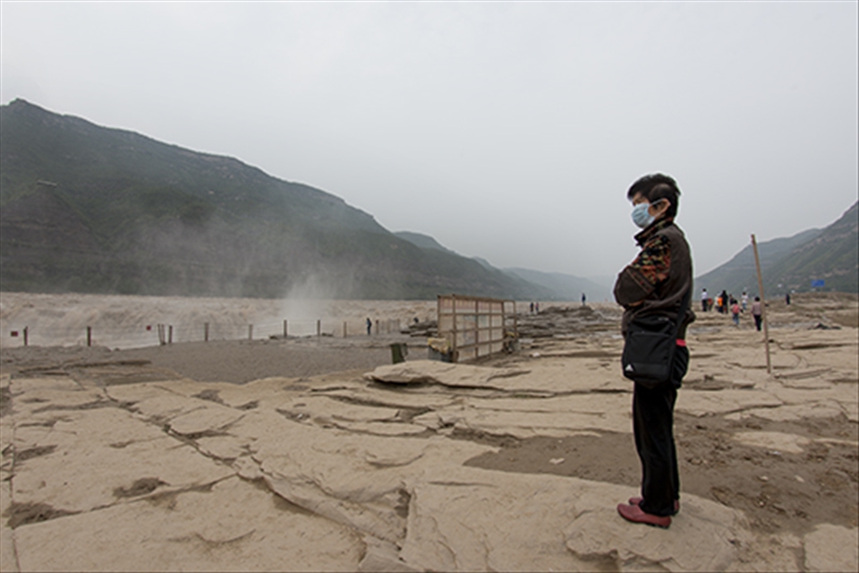 The Hukou waterfall is the largest on the yellow river, and a popular tourist site. Even in rural China, there is still a great deal of pollution, evident here with the dust mask worn. The waterfall spray containing dust and dirt picked up along route. 