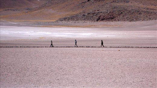 Three people walking in a path that leads to Laguna Miscanti (Chile)