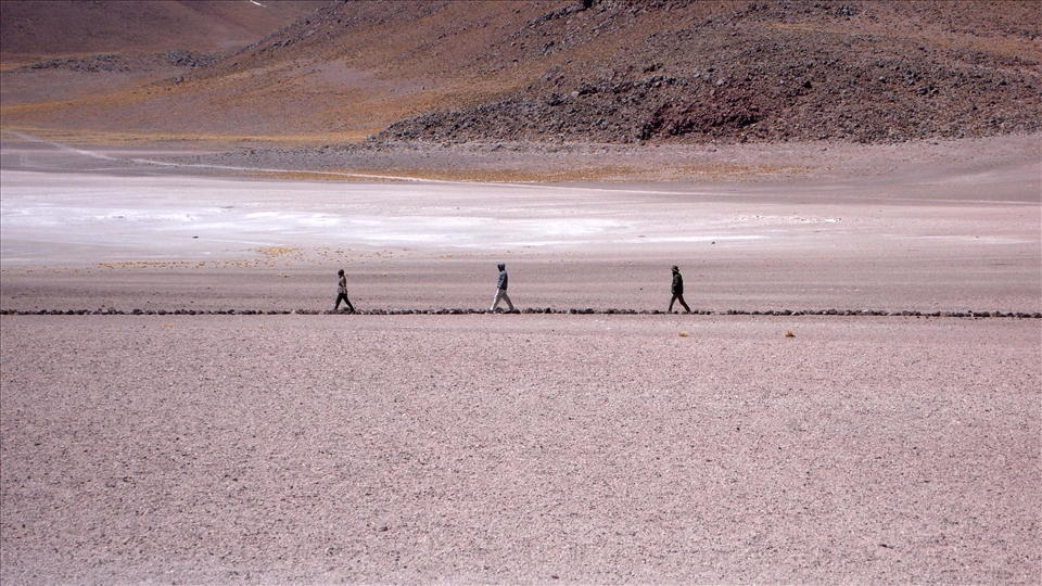 Three people walking in a path that leads to Laguna Miscanti (Chile)
