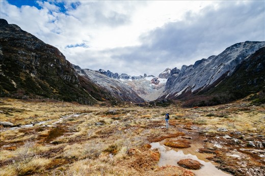 Laguna Esmeralda, Ushuaia, Argentina - On my way to Laguna Esmeralda, you can see how glaciers are melting down as climate is warming up. Everything that looks like pure rock in the mountains was once a big glacier, all its left is that tiny piece of ice at the very top. The hiker is crossing what used to be a massive river coming down from the lagoon at the bottom of the glacier (Laguna Esmeralda), all its left is this spongy tundra and the little river at the left. Still shows how vast the landscape in Patagonia can be.