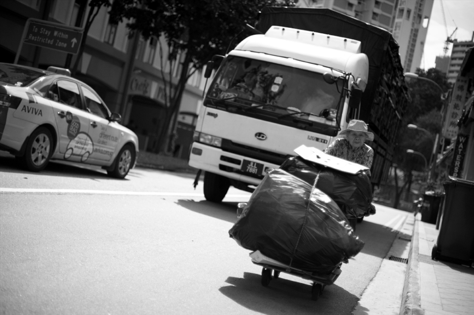 The truck eased almost to a halt, trailing behind the frail looking lady on the two-way street. In this non-welfare city-state, she earns her keep by collecting discarded cardboard and reselling them. After spotting me pointing my camera in her direction, she lowered her head to cut off eye contact. I took my eye off the viewfinder and watched as she inched pass me on her journey.