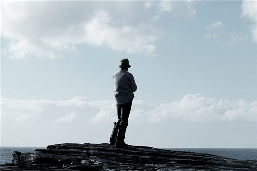 A bushwalker stares out into the ocean.