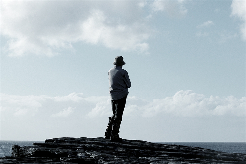 A bushwalker stares out into the ocean.