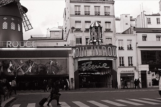 A woman races past Paris's iconic Moulin Rouge without even stopping to give it a glance.