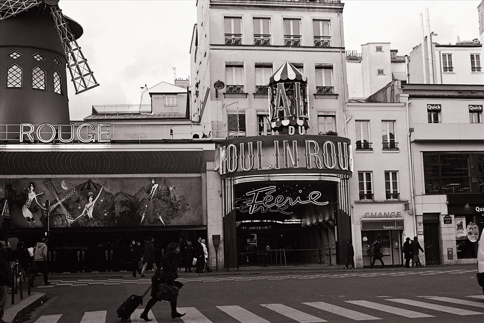 A woman races past Paris's iconic Moulin Rouge without even stopping to give it a glance.