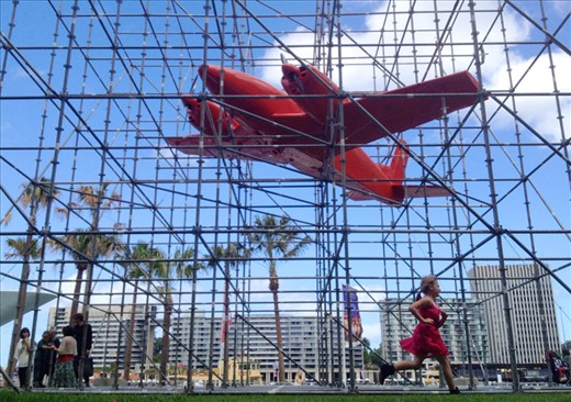 (3) This image of a young girl running past the work “Stasis’ by Claire Healy and Sean Cordeiro outside the front of the Museum of Contemporary Art in Sydney, looks at the idea of active participation in public art.  We can without knowing, be creating art, while observing it. With the plane heading off to the left and the girl running off to the viewers right, I was lucky that her bright pink dress helped to tie the two elements together. 
(This photo was taken with an iPhone)
