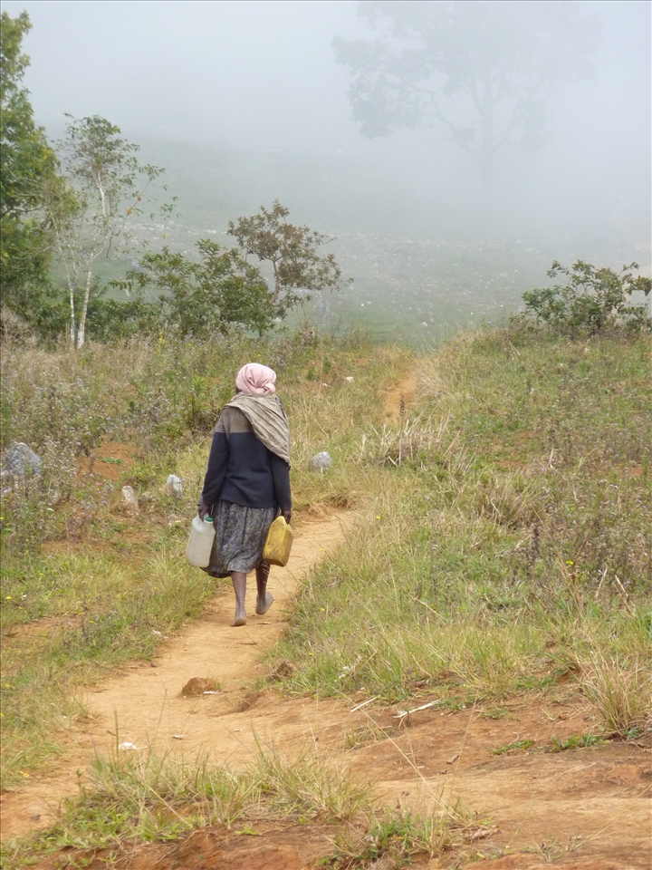 The woman then picks up her water jugs and disappears barefoot into the fog.