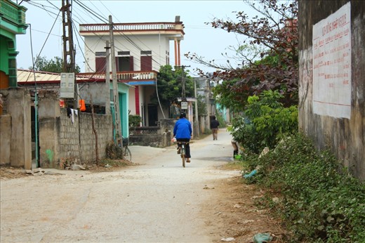 A woman in blue is riding an old bicycle after a long day working.