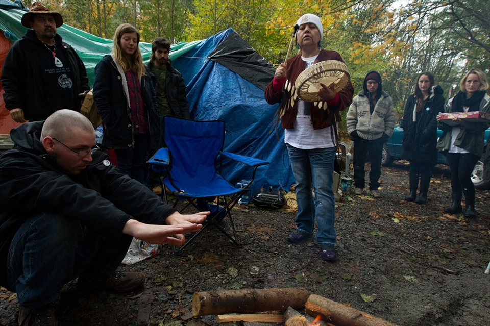 Protestors constructed a camp beside the coordinates of a proposed bore hole site. In this image, Tsoh-thoht, an indigenous woman, plays the drums after she lit the sacred fire. The sacred fire would go on to burn for just over two weeks. 