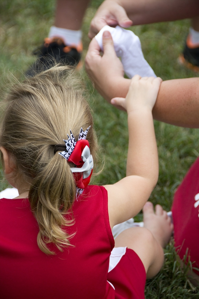 A child was cold and needed her mom to rub her feet and put her socks on. 