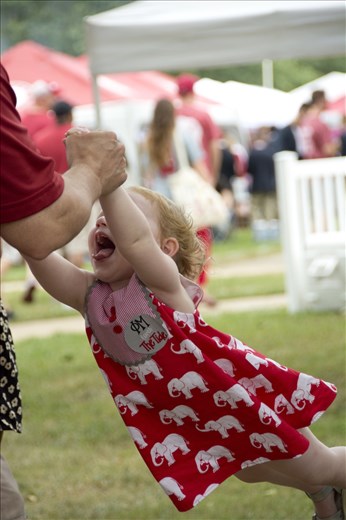 An enthusiastic father completely focused on swinging his daughter, laughing. 