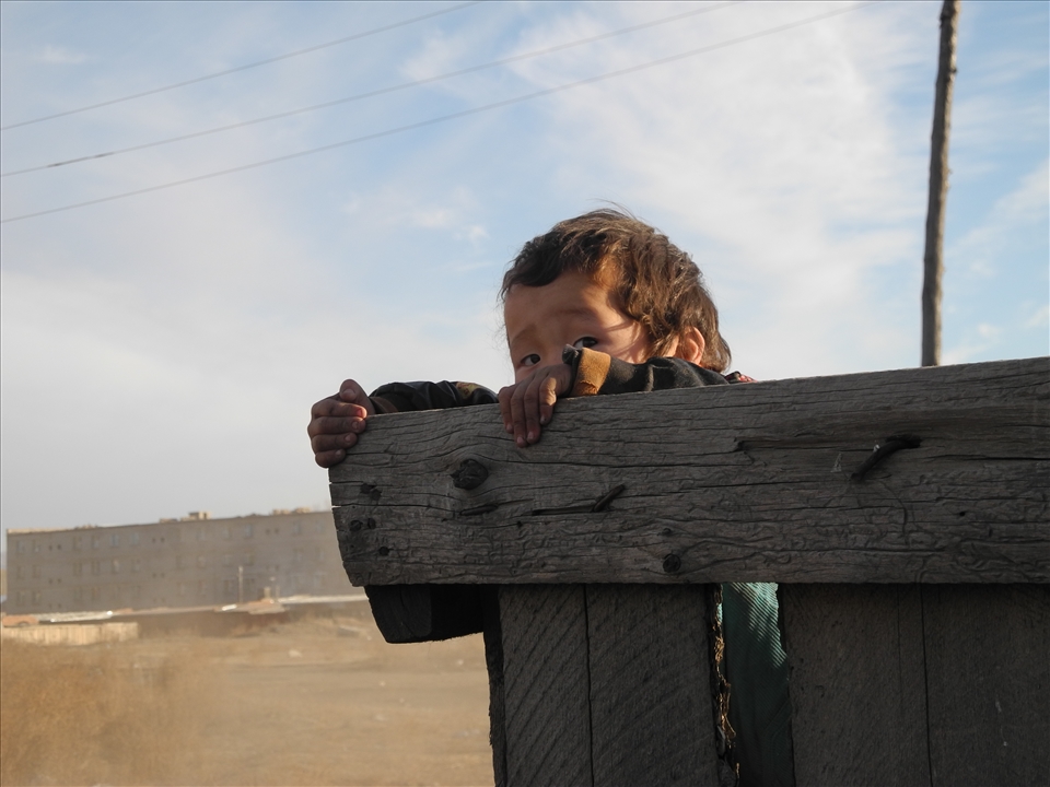 Child looking over a fence. Zuunkharaa, Mongolia
