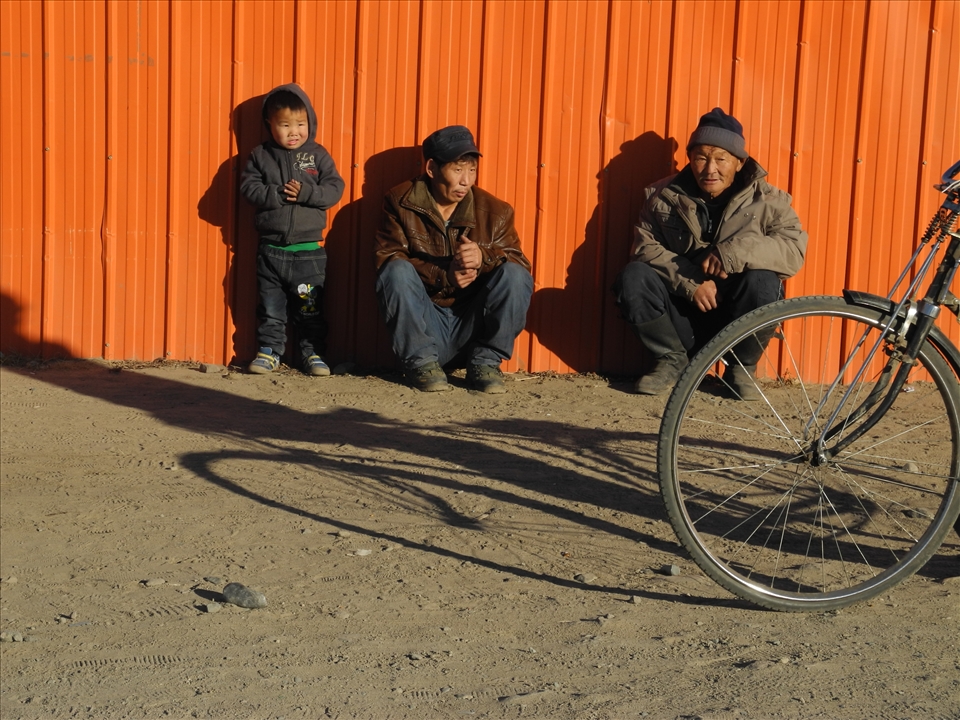 Child, men and bike in the street. Zuunkharaa, Mongolia
