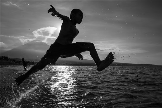 After the Nyepi Day, Bali, a kid washes the bad spirits by jumping in the water.