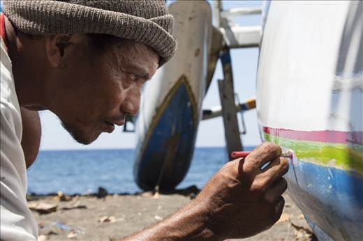 A Bali's fisherman focused on decorating his boat with the traditional colors.