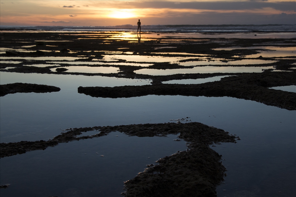 At Balangan Beach, Bali, a girl dances in harmony with the sunset waves.