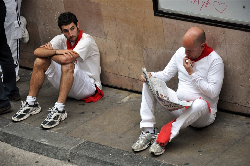 Two men are waiting for the beginning of the  bullrunning. One that looks outwardly calm is reading morning newspaper telling about several yesterday runners were knocked down by furious bulls. //

Every festive morning hundreds of people wearing traditional white clothes and red scarves gather on the old narrow street. All of them bring newspapers. To read and distract their minds form fear. And to hit fearlessly 12 bulls that will run with them to the bullring soon.  

