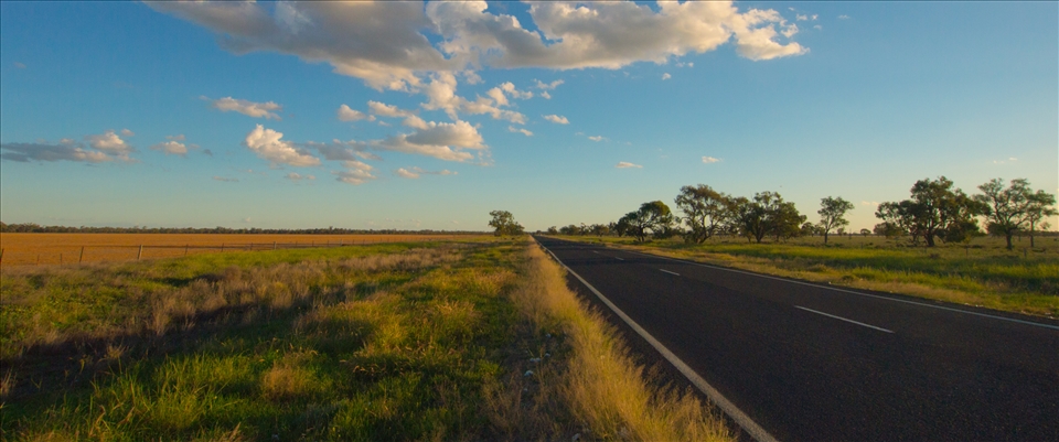 Road to Brewarina:  There can be a certain monotony when travelling the outback roads, until the light fades west and the fields light with the golds and greens of a late fall. The flatness of the land welcomes puffy clouds that seem to tell stories, as I ride in this arid land.