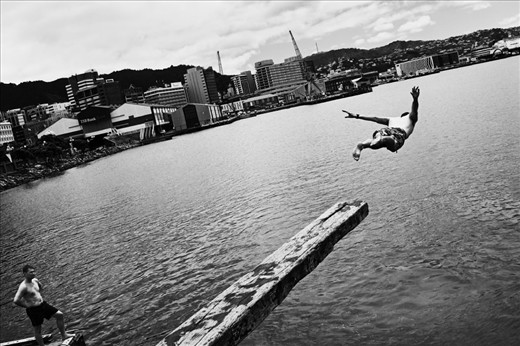 A man leaps into harbour on Wellington city waterfront. This is a favourite spot for swimmers, only minutes from the CBD. Wellington is a pocket-sized city, dominated by the varied surrounding coastline. December 2011.