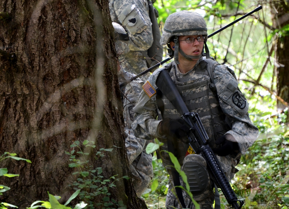 Cadets wait in the woods at Joint Base Lewis-McChord during a combat training on the live fire range. Cadets are put through combat scenarios with live amo and distractions like smoke bombs but are expected to move, communicate and work as a team 